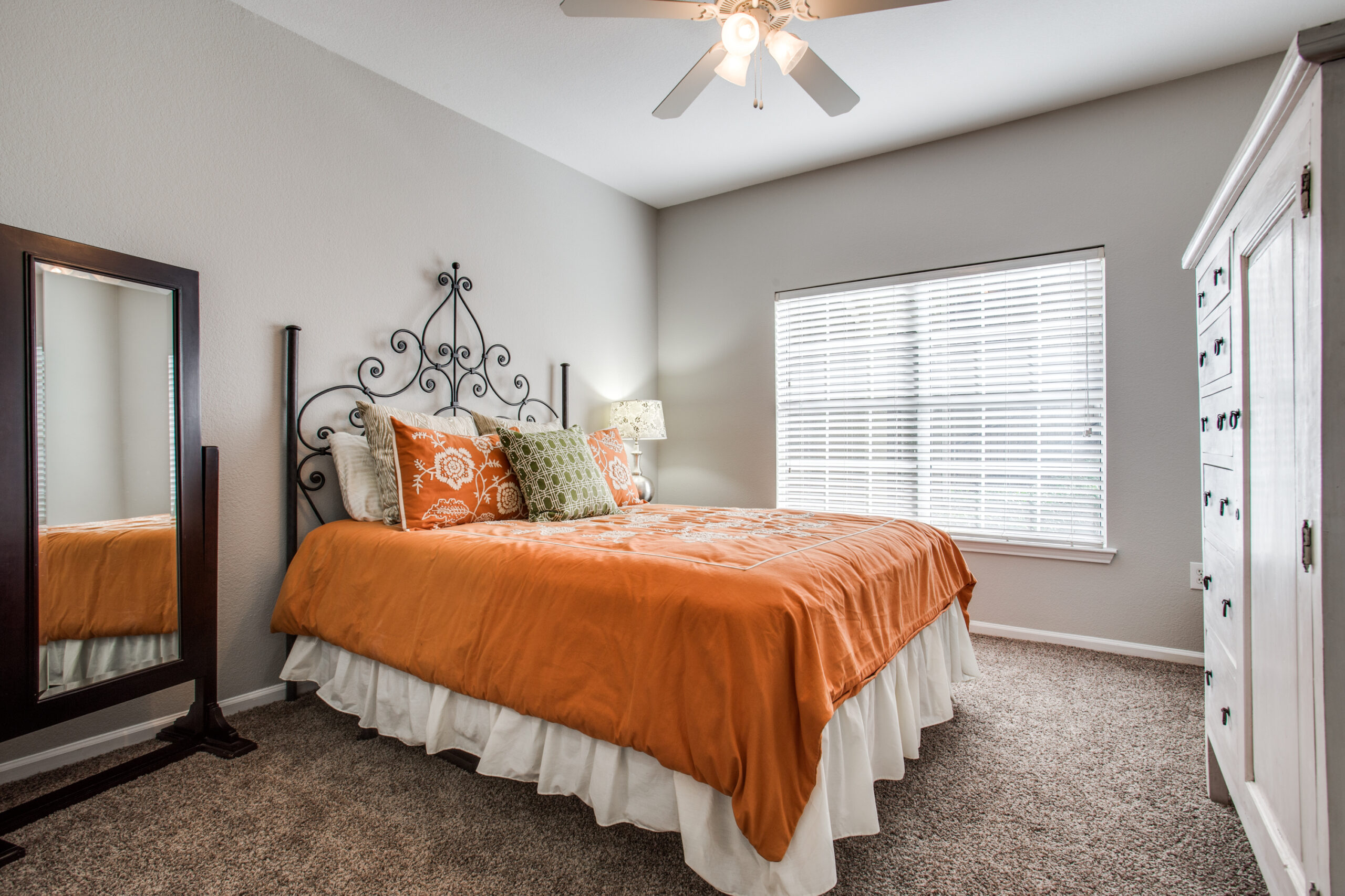 model bedroom with orange theme color, carpeted floors and ceiling fan